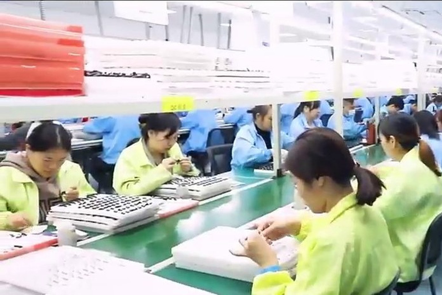 Assembly line at a Shenzhen partner factory with operators working at stations along a green conveyor